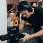 Filmcrew-Mitglied mit Kamera und Kopfhörern beim Dreh eines Videotestimonials